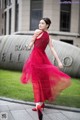 A woman in a red dress is walking down the street.