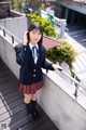 A woman in a school uniform standing on a balcony.