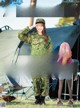 A woman in a military uniform salutes as she stands in front of a tent.