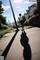 A woman walking down a street with her shadow on the ground.