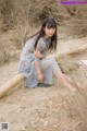 A woman sitting on a log in the sand.