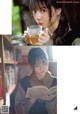 A woman holding a cup of tea and reading a book.