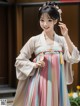 A woman in a pink and blue hanbok is posing for a picture.