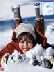 A woman laying in the snow with her feet up in the air.