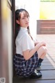 A young woman in a school uniform leaning against a wall.