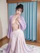 A woman in a purple kimono is posing naked on a bed.