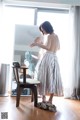 A woman standing in front of a mirror holding a bra.