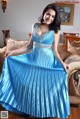 A woman in a blue dress sitting on a couch.