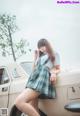 A woman in a school uniform leaning on a car.