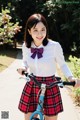 A woman in a school uniform riding a bike.