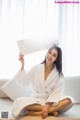 A woman in a bathrobe holding up a sign.