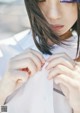 A woman in a white shirt is adjusting her tie.