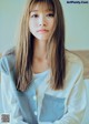 A woman with long brown hair wearing a white shirt.