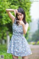 A woman in a blue dress making a peace sign with her hands.