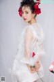 A woman in a white dress holding a bouquet of red roses.