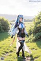 A woman with long blue hair standing in a field.