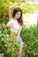 A woman in a white tank top and denim shorts posing for a picture.