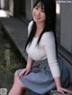 A woman sitting on a wooden bench in a skirt.