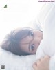 A woman laying in bed under a white blanket.